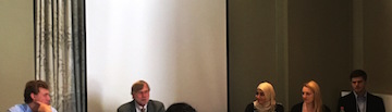 People sitting at a panel discussion with a bright window behind them.