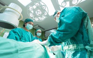 Healthcare professionals performing surgery under bright surgical lights in an operating room.