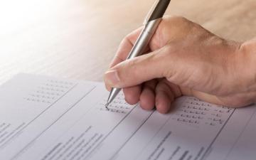 A person is filling out a paper survey with questions and checkboxes