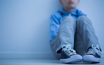A person sitting against a wall with knees drawn up.