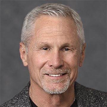 A smiling man against a grey background.