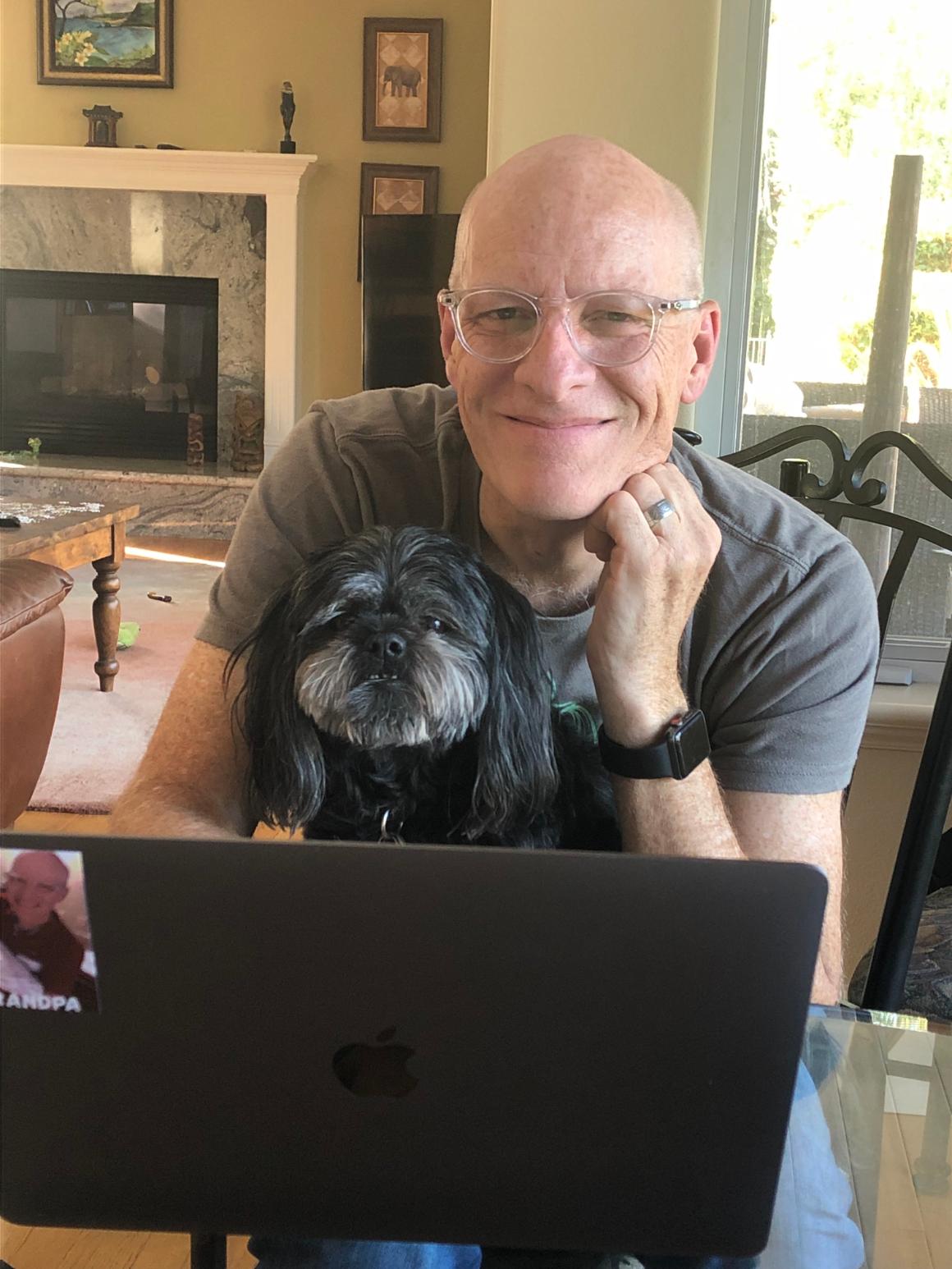 A person smiling while working on a laptop at home.