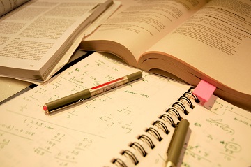 Open books and a notebook with a pencil and eraser on top.