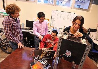 Four people collaborating around a computer in an office setting.