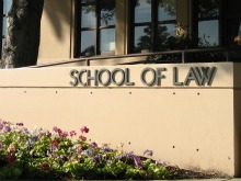 Building sign reading School of Law with flowers in front.